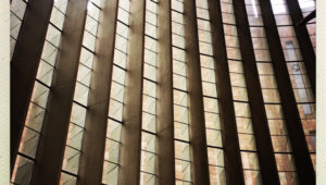 Verticle louvre windows at Coventry Cathedral. The windows are arranged on a curve. The window frames are deep, creating strong shadows and deep contrasts in the photo.