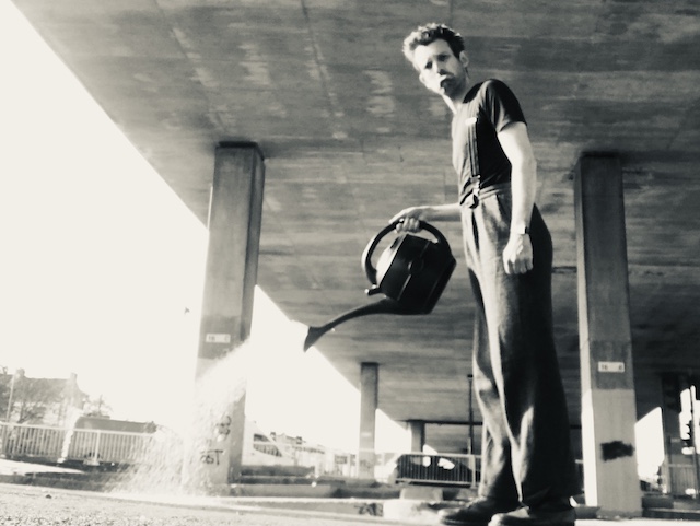 To illustrate a blog post called fear holds back my imagination, Oliver Broadbent stands under a motorway bridge watering a patch of concrete