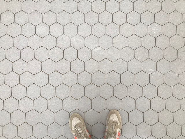 Hexagon floor tiles with someone's white trainers just poking into the bottom of the frame